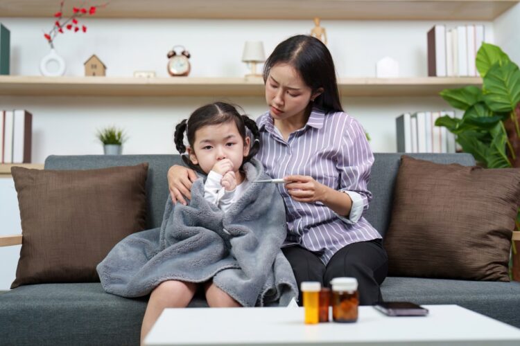 A mother comforts her sick daughter while checking her temperature. A scene of care and concern in a cozy living room.